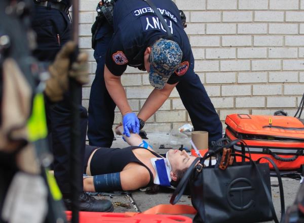 A paramedic attends to a woman with a neck brace on the sidewalk after the Gramercy crash.