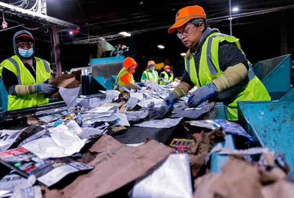 Martina Garcia, right, works on the paper quality co<em></em>ntrol line at a So<em></em>noco materials recovery facility on Tuesday, Jan. 17, 2023, in Raleigh, N.C. The recycling plant receives material from all of Raleigh’s residential blue bins, along with recycling from Durham, Fuquay-Varina and some smaller community drop-off centers.