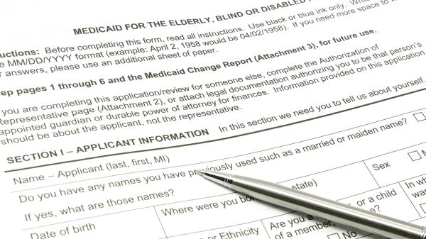 A Medicaid application ready to be filled out with a silver pen.