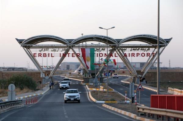 A view of the road leading to the Erbil Internatio<em></em>nal Airport, which goes under a sign and cement awning.