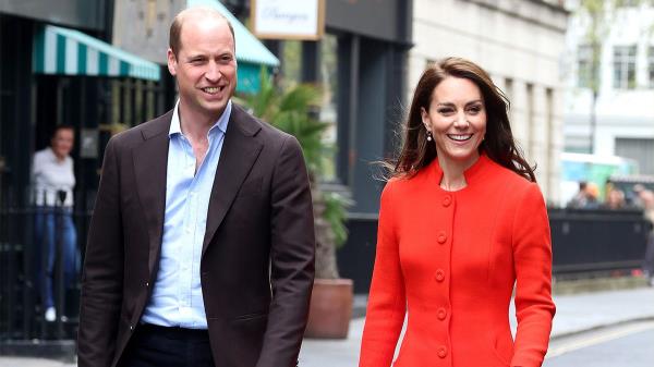 Prince William smiles as he walks alo<em></em>ngside Kate Middleton in a red dress