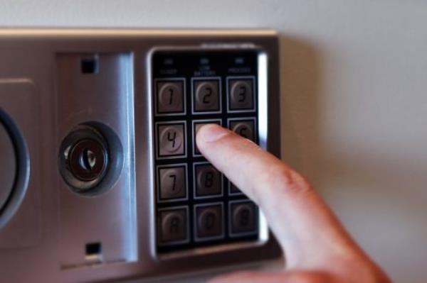 Blurred safe with combination lock and human hand in a hotel room, closeup numbers with tilt shift effect. Selec<em></em>tive focus.