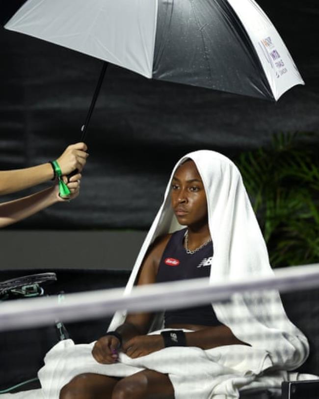 Coco Gauff waits under an umbrella during a rain delay while playing Jessica Pegula in the WTA Finals.