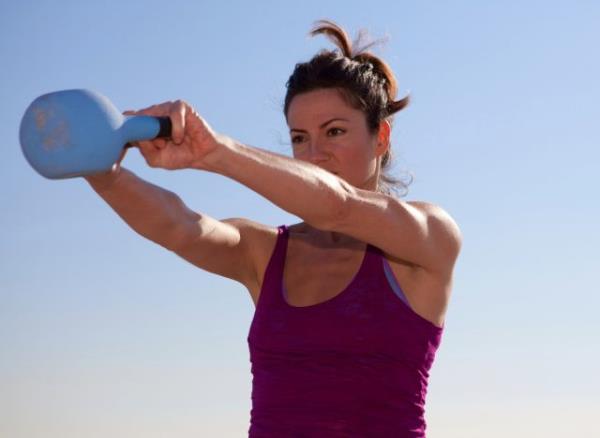 woman doing kettlebell swings, co<em></em>ncept of strength exercises for women to melt middle-aged spread belly fat