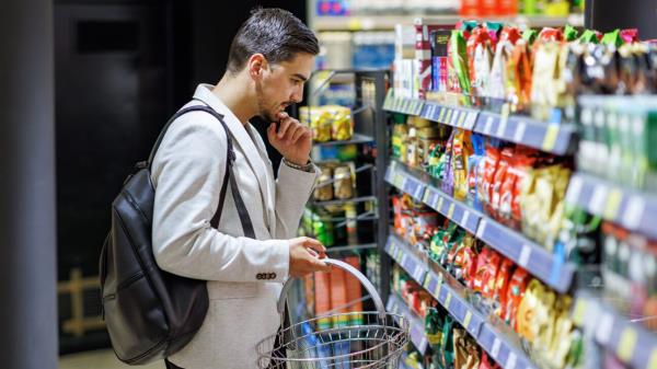 Man looks at shelves of chips.