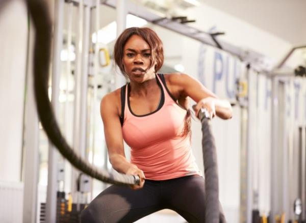 woman working with battle ropes, HIIT