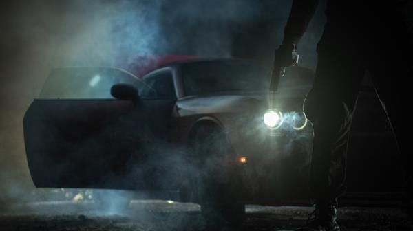 Man holding gun in front of sports car