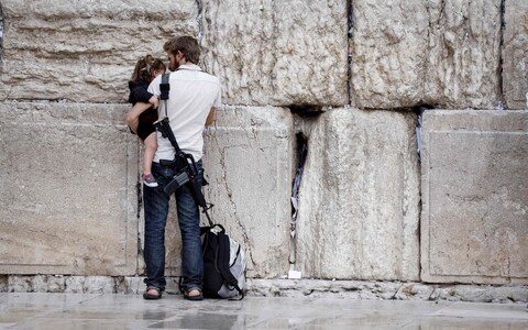 An armed Jewish man holds a child as he prays at the Western Wall in Jerusalem's Old City on November 12, 2023.