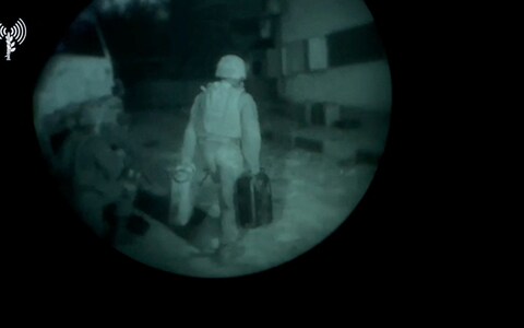 An Israeli army soldier walks towards a building structure carrying gallon containers, as they say, while delivering fuel to Al Shifa hospital, in a location given as Gaza, in this screengrab taken from a handout video released on November 12, 2023. 