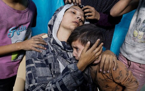 A Palestinian woman and children react after Israeli strikes, at a hospital in Khan Younis in the southern Gaza Strip November 13, 2023. 