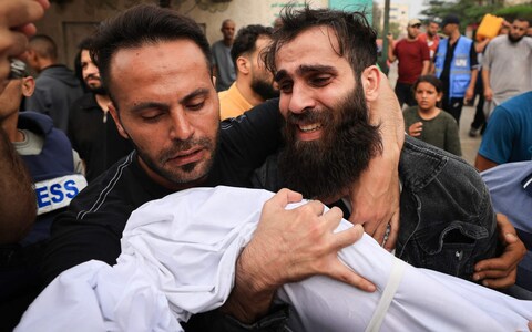 The father (R) of a young boy from the al-Aqad family, reacts as he holds the body of his child, killed an Israeli strike on Khan Yunis in the southern Gaza Strip