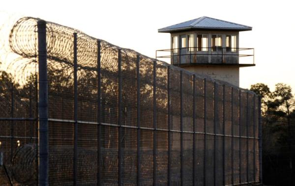 The sun sets behind Holman Prison in Atmore, Ala., on Thursday, Jan., 27, 2022, as the U.S. Supreme Court co<em></em>nsidered whether to allow the execution of death row inmate Matthew Reeves, co<em></em>nvicted of killing a man during a robbery in 1996. (AP Photo/Jay Reeves)