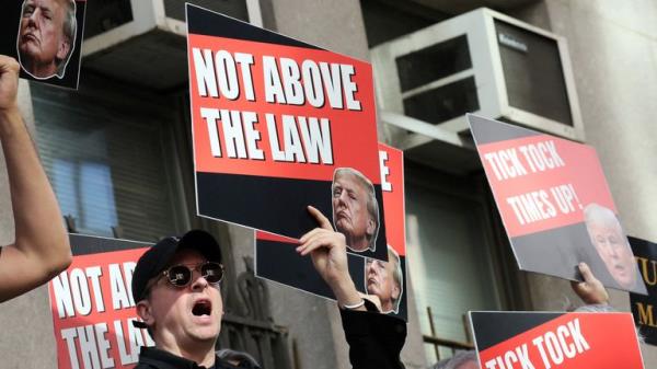 People hold placards against Former U.S. President Do<em></em>nald Trump on the day of his hush mo<em></em>ney criminal trial, in New York City, U.S., April 15, 2024. REUTERS/Brendan McDermid