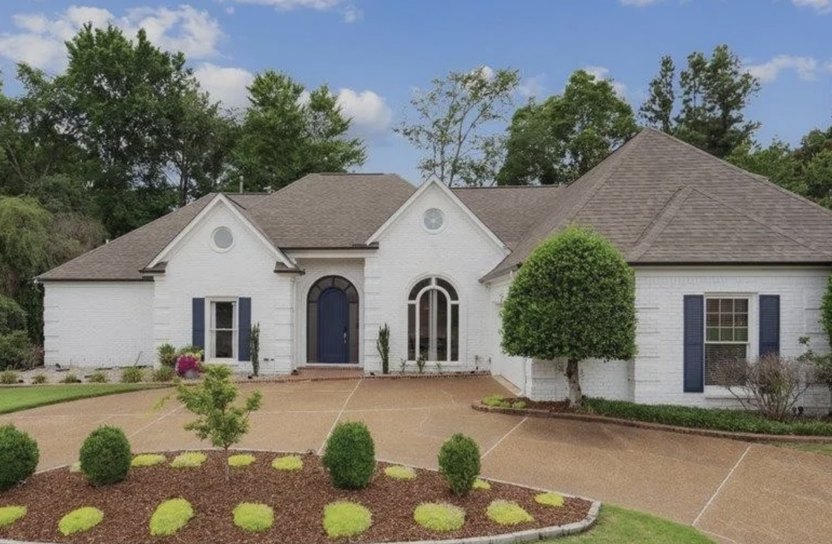 White home with manicured shrubbery in front of it.