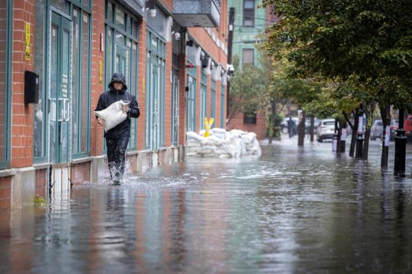 A person carries sands bags through water as heavy rains cause streets to flood in Hoboken, N.J., on Sept. 29, 2023.