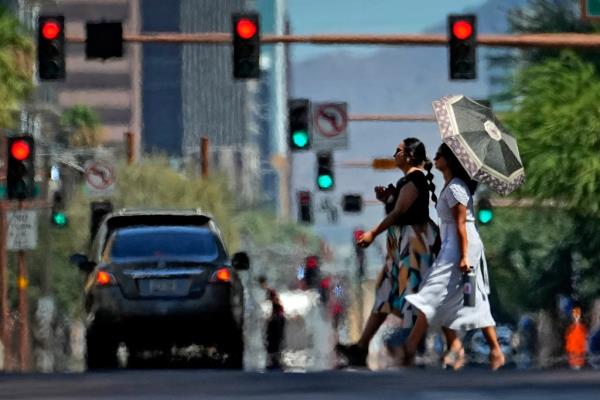 Heat ripples engulf two ladies while crossing the street on July 17, 2023, in downtown Phoenix. 