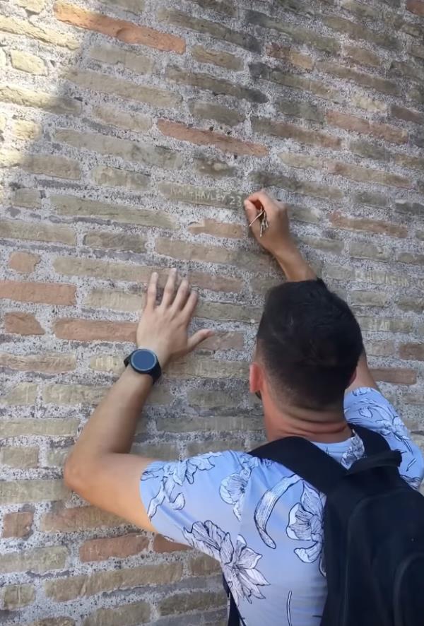 Tourist carving names into Colosseum wall