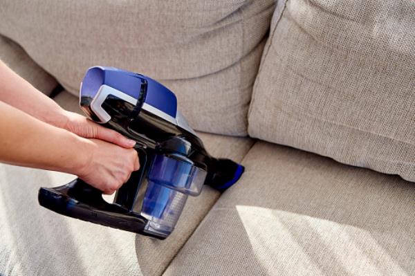 A woman vacuuming a sofa 