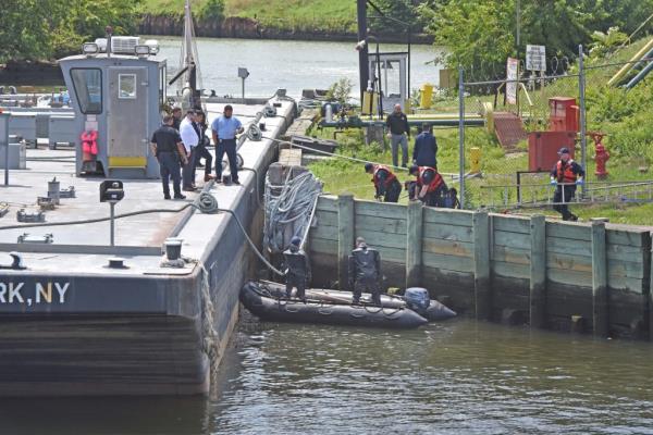 NYPD officers are pictured retrieving a body from the water in the Newtown Creek near the Metropolitan Avenue bridge. 