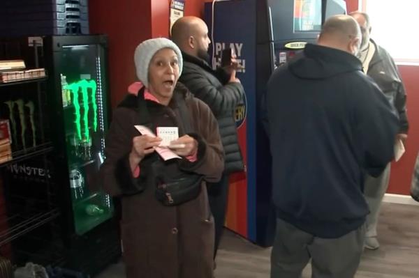 A woman in a hat holds up her lotto tickets inside the store. 