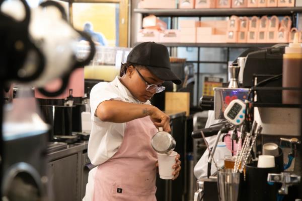 barista at Moka Matcha Cafe , pouring coffee from small silver pitcher into cup