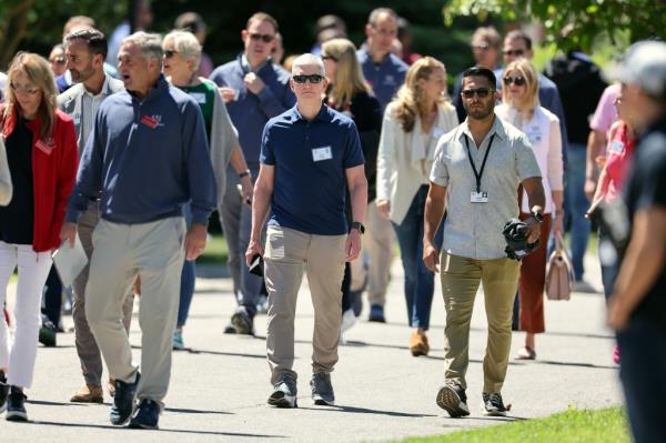 Tim Cook (C), CEO of Apple leaves a morning session at the conference. 