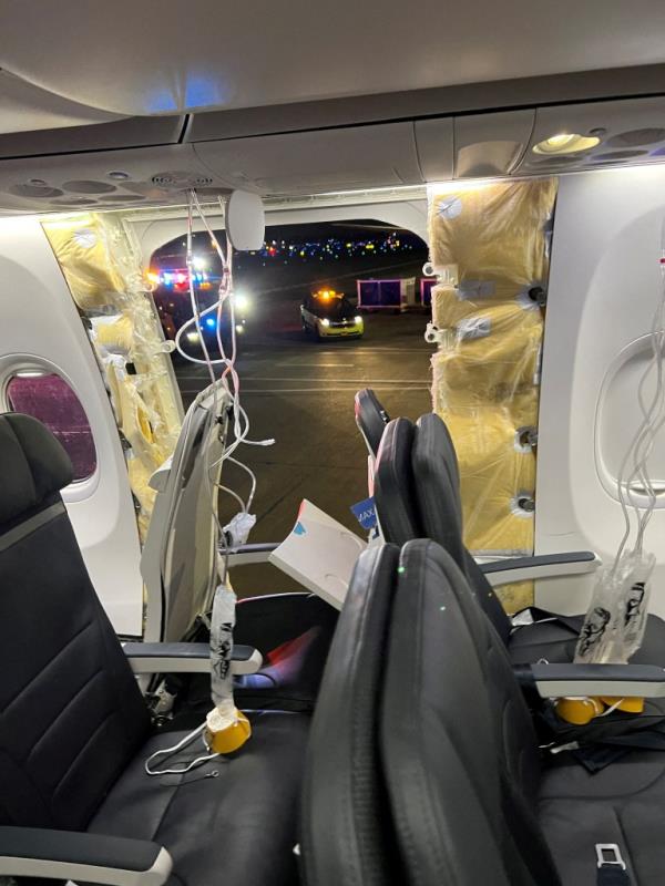 Passenger oxygen masks hang from the roof next to a missing window and a portion of a side wall of an Alaska Airlines Flight 1282 in Portland, Ore., on Jan 5, 2024. 