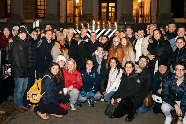 Students, teachers, and Claudine Gay pose in front of the menorah at Harvard