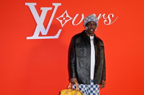 Lil Yachty attends Louis Vuitton Menswear Fall/Winter 2024-2025 show, wearing black jacket and blue and white patterned pants in Paris.