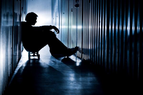 Depressed man sitting alone in a hallway