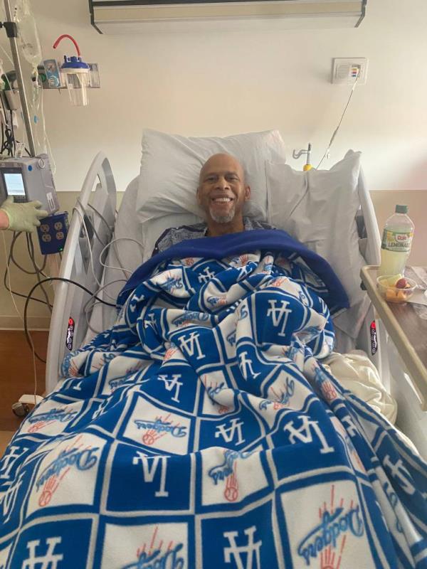 Kareem Abdul-Jabbar, all smiles, laying down in his hospital bed.