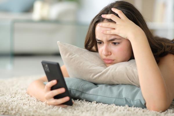 Worried woman checking phone on the floor.