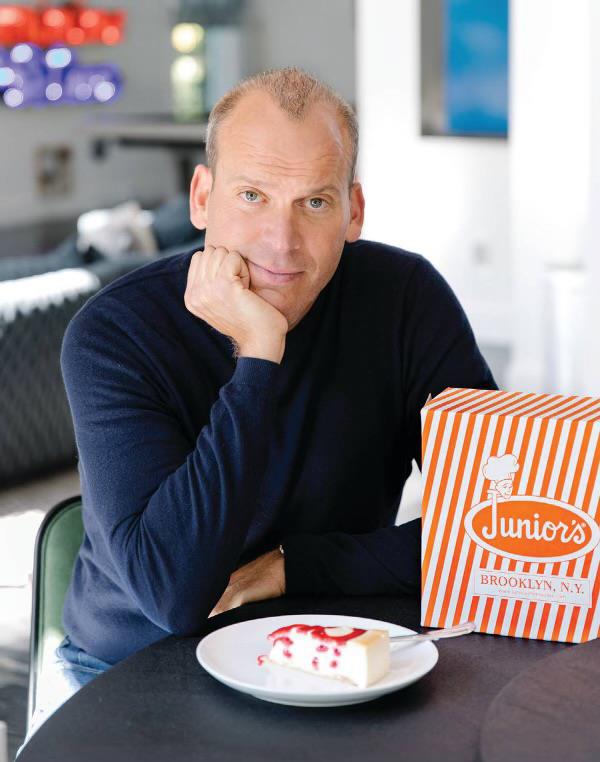 Alan Rosen, owner of Junior's Restaurant, sitting at a table with a plate of cake and a box of food, speaking a<em></em>bout the declining state of New York City