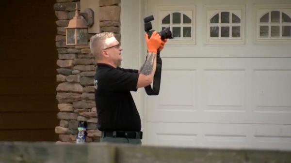 A crime scene photographer seen working at the scene of a murder-suicide in Inverness, Florida 