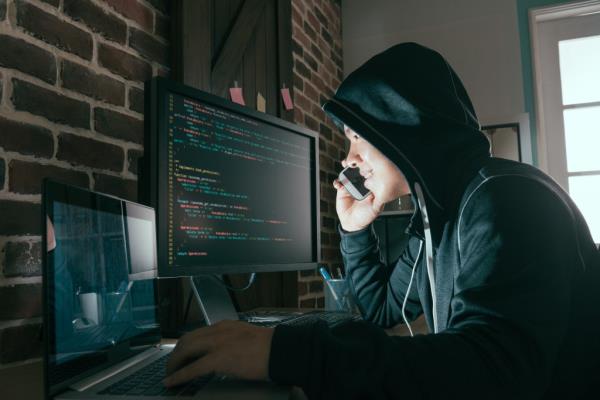 A hacker on their phone calling for a victim, potentially stealing perso<em></em>nal information through data and scamming for ransom.