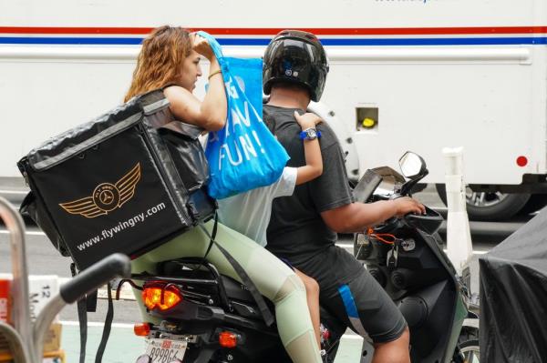 A man and woman riding on a moped.