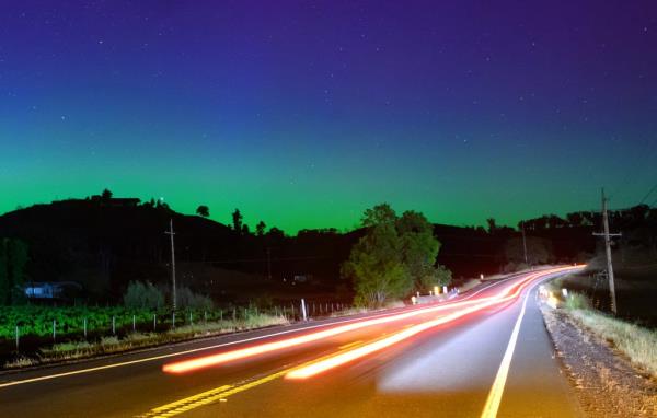 Northern lights illuminating the night sky above a highway in Middletown, California during a powerful solar storm.