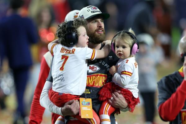 Harrison Butker holding his two kids on the field.