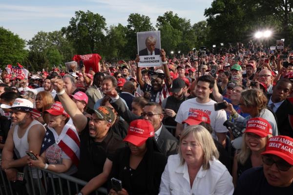 A supporter in the crowd holding up Trump's mugshot.