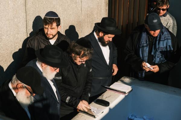 A group of men in suits looking over a gravesite.