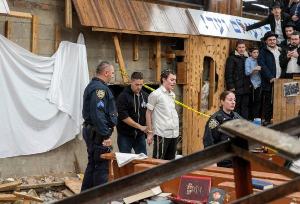 New York Police officers arrest a Hasidic Jewish student after he was removed from a breach in the wall of the synagogue that led to a tunnel dug by students.