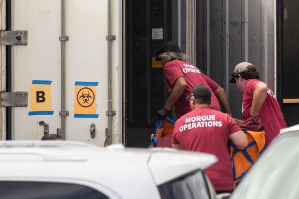 Workers move a body bag into a refrigerated storage co<em></em>ntainer as mobile morgue vehicles arrived on the Hawaiian island.