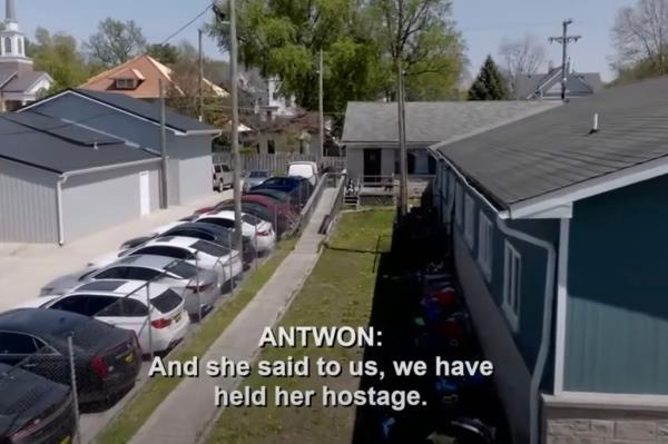 A shot of cars parked and the back of several houses. 