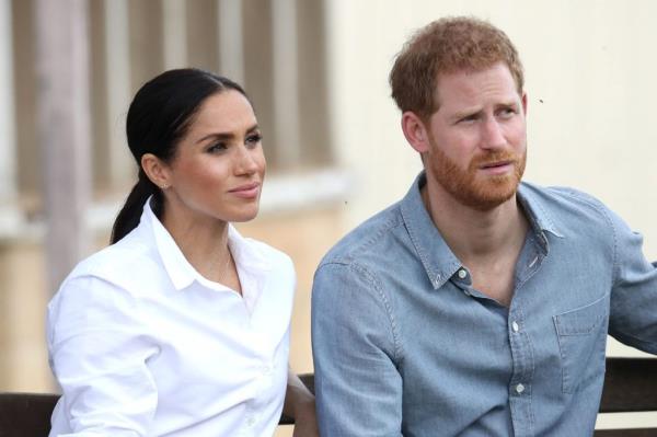 Prince Harry and Meghan, Duchess of Sussex, sitting on a bench while visiting the Woodley family farm in Dubbo, Australia during their Autumn tour