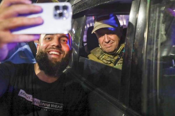 Yevgeny Prigozhin, right, sits inside a military vehicle posing for a selfie photo with a local civilian on a street in Rostov-on-Don, Russia, Saturday, June 24, 2023, prior to leaving an area of the headquarters of the Southern Military District.