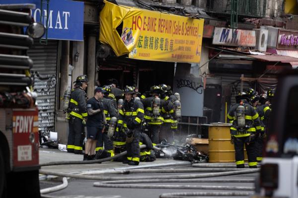 Firefighters douse E-scooters and E-bike batteries seen piled up on the sidewalk in front of 80 Madison St. in Manhattan, Friday, June 23, 2023.