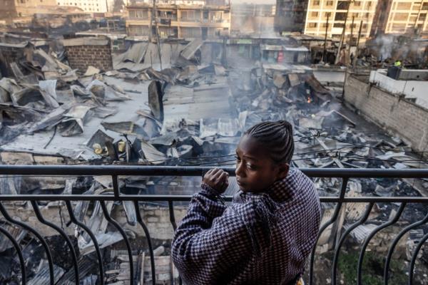 A woman looks from a balcony at the heavily damaged houses and shops, a day after a gas explosion in the Embakasi area of Nairobi, on February 2, 2024.