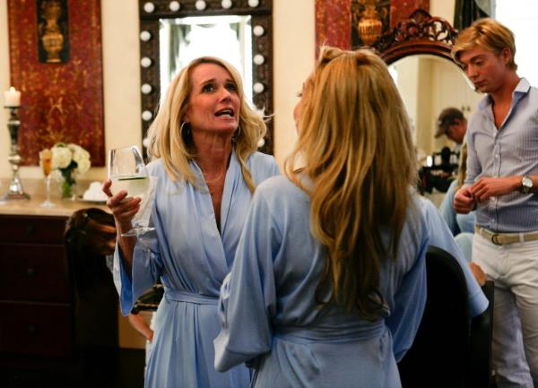 Kim Richards holding a glass of wine wearing a robe. 