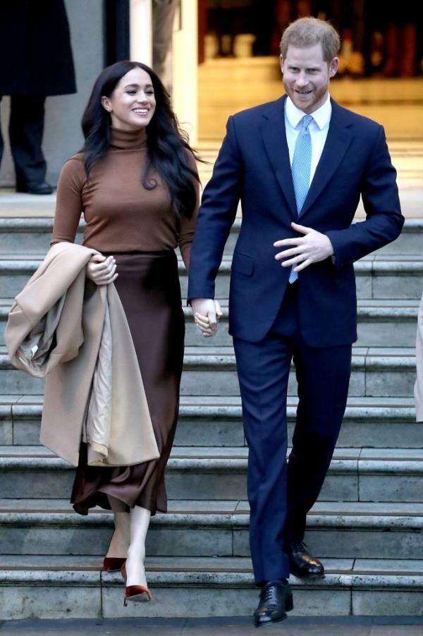 Prince Harry and Meghan Markle walking down stairs while holding hands outside of Canada House in London.