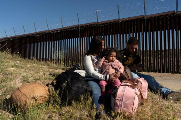 Asylum-seeking migrant family from Brazil, Edicarla, Mauricio, and their baby daughter Helena, sitting on the ground waiting for U.S. Border Patrol in Jacumba Hot Springs, California